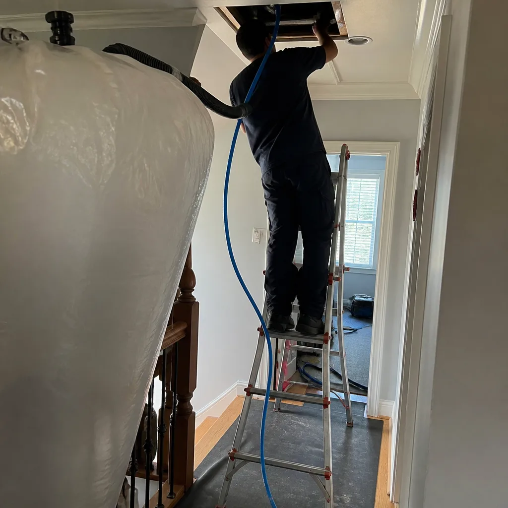 Professional technician performing residential air duct cleaning service with vacuum equipment